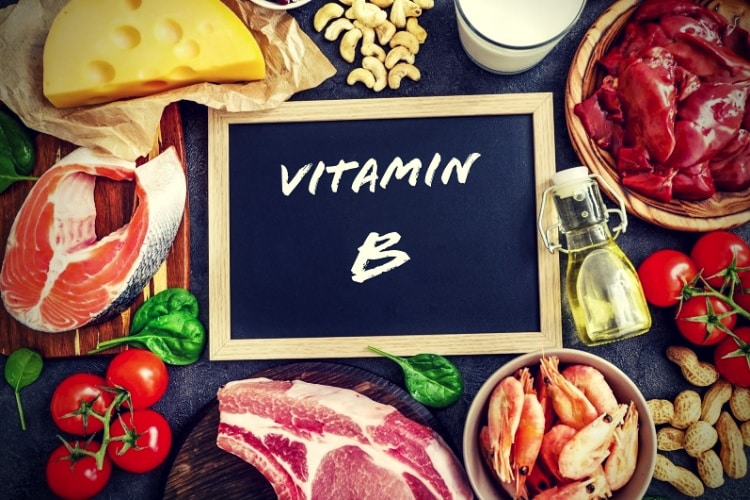 Assortment of high vitamin B sources on dark background, milk, liver, olive oil, tomatoes, prawns, peanuts, beef, spinach, salmon, keshew, cheese. Top view.