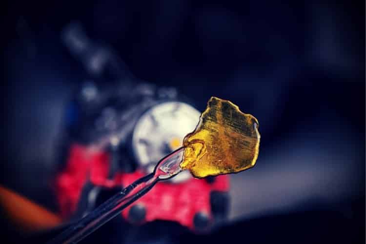 Cannabis oil concentrate aka shatter (train wreck strain) with dabbing tool against dark background