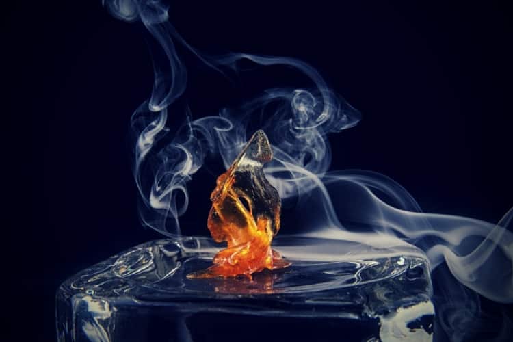 Cannabis oil concentrate aka shatter with smoke isolated over dark background