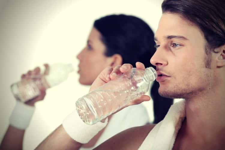 Couple in gym drinking water