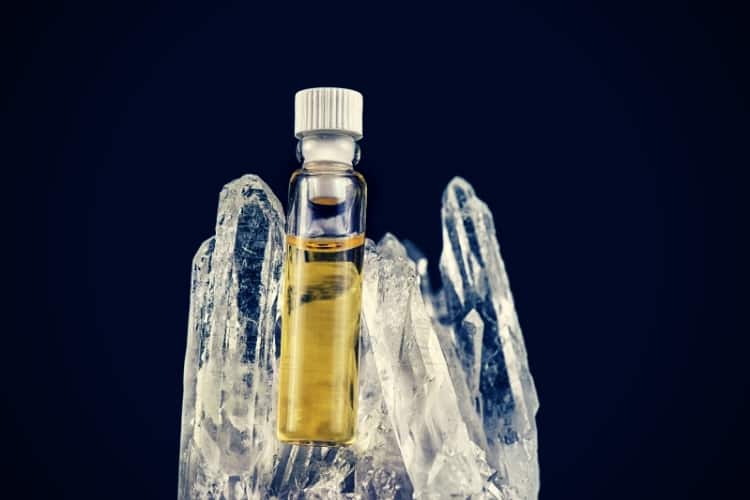 Detail of cannabis oil container and quartz crystal isolated on black