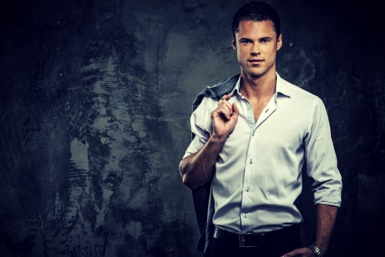 Handsome man in shirt against grunge wall holding jacket over shoulder Handsome man in shirt against grunge wall holding jacket over shoulder