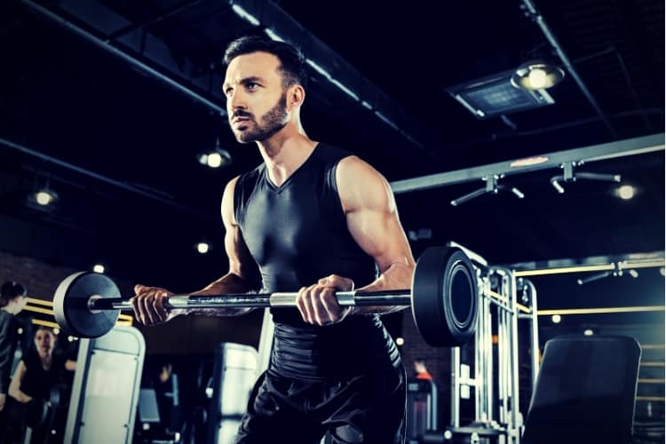 Low angle view of athletic man exercising with heavy barbell in gym Low angle view of athletic man exercising with heavy barbell in gym