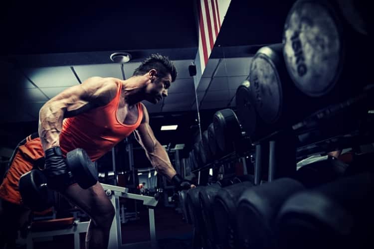 Very power athletic guy standing with barbell