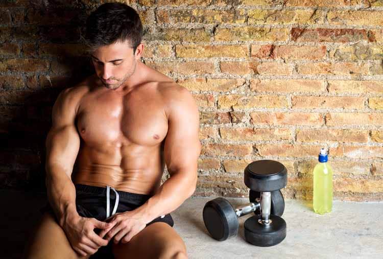 muscle man relaxed with weights and drink
