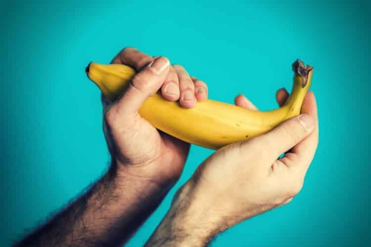 two hands of a man holding a banana